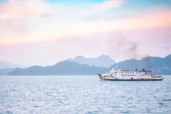 Güzel gün batımı dağ ve feribot tekne ufuk deniz tarağı denizde akşam arka plan üzerinde ada yolcu taşıma ile. Altın ışık ile su taşımacılığında yaz tatili doğa manzarası.