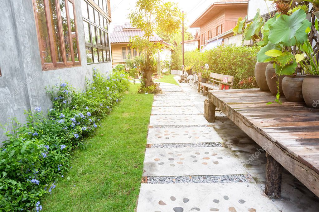 Landscape garden. Stone pathway in tropical garden. Stone walking way made from cement and pebble with green lawn in countryside. Outdoor garden exterior design.
