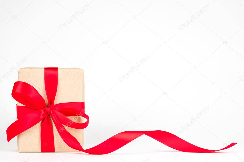 Wrapped handmade craft paper brown gift box with red ribbon bow isolated on white background. Valentine, Christmas, New Year and happy birthday present decoration.