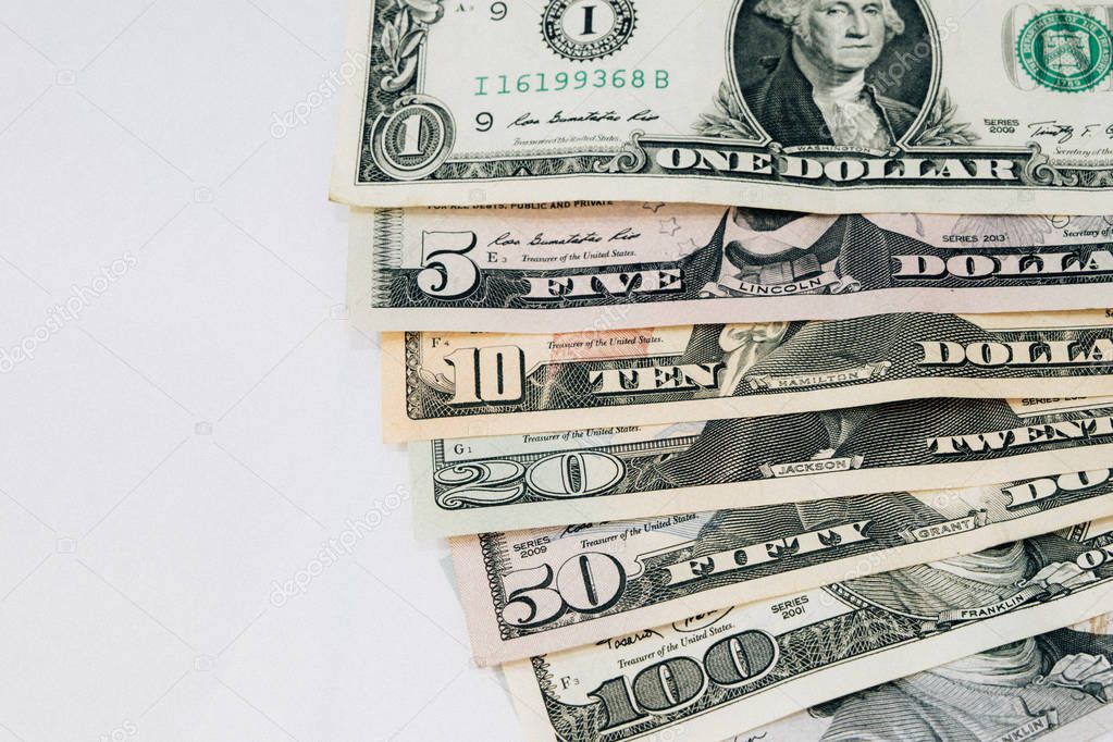 Pile of various US american dollar money bills spread as fan sorted by value of dollar banknotes on white background used for money concept and background.