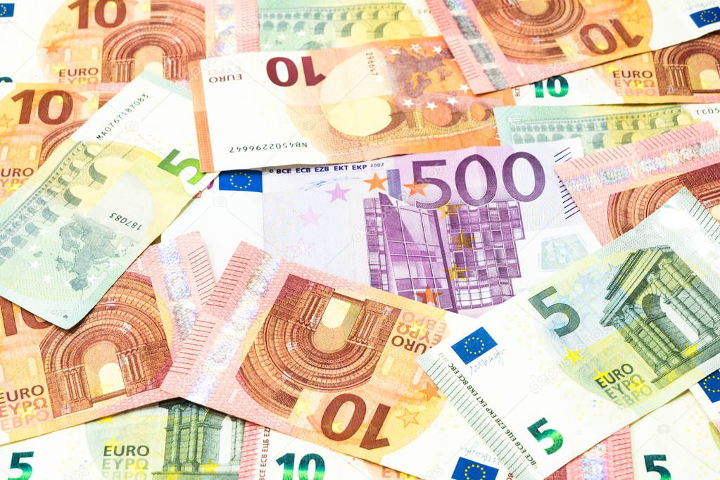 Five hundred euro bill in pile of five and ten euros banknotes background.
