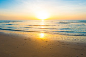 Gyönyörű napfelkelte trópusi homokos strandján, a reggeli napsütésben a fényes nap a strandon.