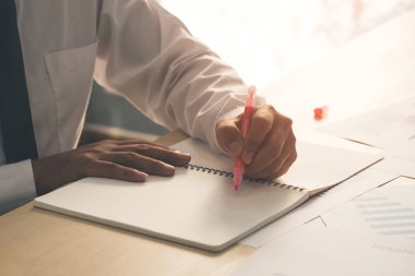 Başarı işadamı el el üstünde pembe marker kalem tutan ve fikir veya bazı şeyleri defter ile ev ve ofis ahşap tablo iş kağıt üzerinde yazılı. İş ve eğitim kavramı.