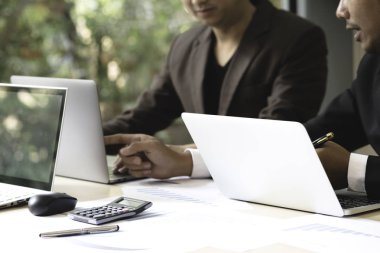Ofiste toplantı sırasında dizüstü ve touch kullanarak iki genç işadamları yastık. Girişimciler el sırasında tartışma ve tasarım fikir ekranında işaret ve çalışma alanı'ndaki ahşap masa üzerinde planlama.