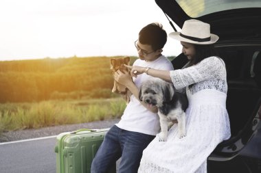 Hayattan zevk mutlu ve Genç Asyalı Çift Evcil ile seyahat. Kırsal köpeklerle oynamak araba bagajı oturan çift yolcuları. Genç aile yaşam tarzı seyahat macera ve açık hava tatil.