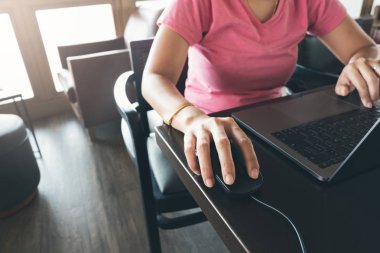 Laptop ile tablo üzerinde çalışma, tıkırtı fare ve kafede otururken yazarak genç serbest kadın el kapatın. Online çalışma ve öğrenme iş kadın giyim gündelik elbise bağlanmak Internet.