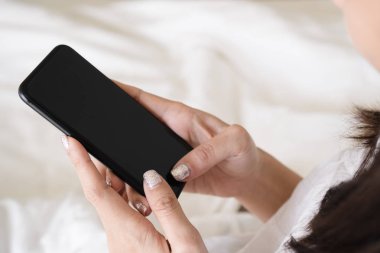Kadın el sabah yatakta yatan süre ile boş masaüstü ekran siyah smartphone kullanarak kapatın. Kadın kişi iş ve cep telefonu ile sosyal uygulamalar sabah erken uyanma sonra kontrol.