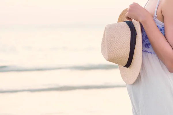 种植在热带海滩上的迷人和快乐的妇女形象 手捧草帽在暑假与复制空间 年轻女孩穿着白色礼服独自行走在海上在日落 — 图库照片