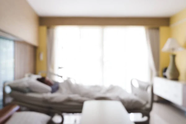 Blurred background of patient lying on bed in hospital room with nature light from window. Blurry image of recovery room with bed and comfortable medical equipped for patient for background.