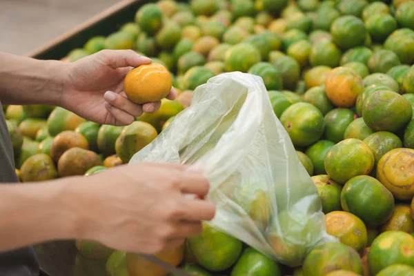 Закройте Руки Человека Покупка Сбор Свежих Апельсинов Положить Пластиковый Пакет — стоковое фото