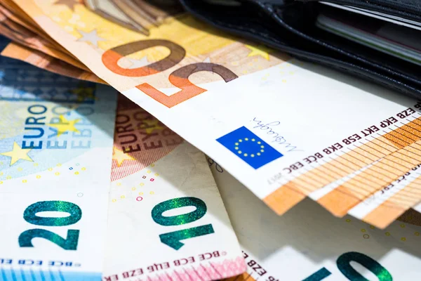 Pile of various kinds euro banknotes on desk with black leather wallet use for money or currency background and financial concepts.