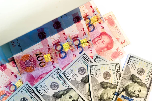 伪造美元货币检测 在白色背景下用紫外光或黑光机检查100美元和人民币纸币 — 图库照片