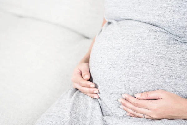 Zbliżenie Dłoni Młoda Piękna Kobieta Ciąży Dotykając Jej Brzuch Siedząc — Zdjęcie stockowe