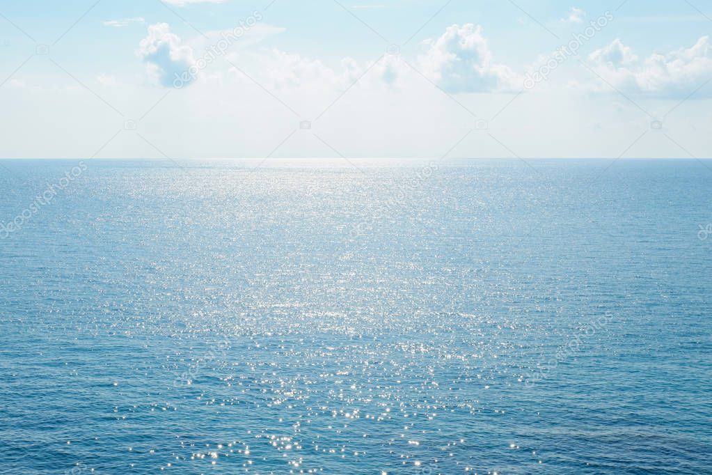 Clear blue sky and sea surface sparkling with sunlight.