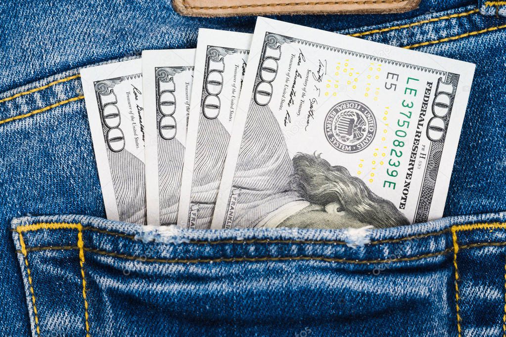 Close up money in pocket of blue jean. One hundred dollar bills in back of jean pocket.