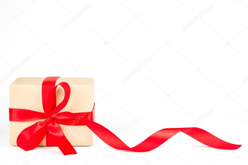 Wrapped handmade craft paper brown gift box with red ribbon bow isolated on white background. Valentine, Christmas, New Year and happy birthday present decoration.