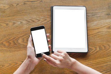 Dijital tablet pc ile tahta masada otururken Smartphone ile boş ekran kullanan kadın