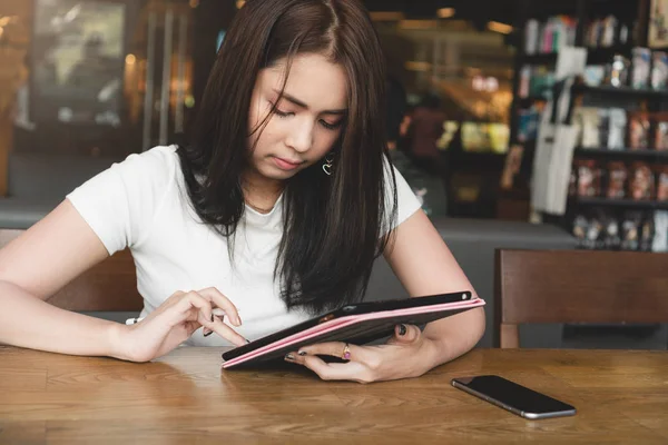 beautiful asian woman reading ebook with digital tablet while sitting at table with smartphone in cafe, digital marketing and education concept