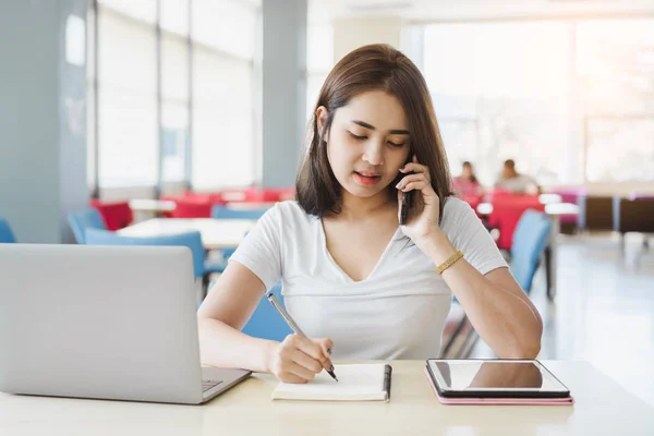 Junge Asiatische Geschäftsfrau Spricht Smartphone Und Notiert Notebook Während Sie — Stockfoto