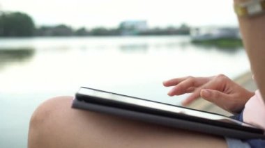 Genç Asyalı kadın el dijital tablet bilgisayar bilgi internet üzerinde arama kullanarak yakın açık akşam Nehri yakınında. El çalışma ve tablet ile yazarak.