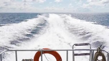 Lifebuoy ile derin mavi denizde tam hız disk ile taşıyarak sürat teknesi teknenin kıç üzerinde su köpük ve yüzey arkasında ile yaz gökyüzü üzerinde asılı. Denizde taşıma motorlu tekne.