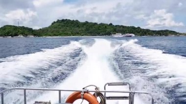 Lifebuoy ile derin mavi denizde tam hız disk ile taşıyarak sürat teknesi teknenin kıç üzerinde su köpük ve yüzey arkasında ile yaz gökyüzü üzerinde asılı. Denizde taşıma motorlu tekne.