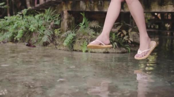 慢动作的年轻女子坐在湖边的木桥上 在水面上晃动脚 在傍晚的夏天享受生活 愉快的冒险旅行假期 — 图库视频影像