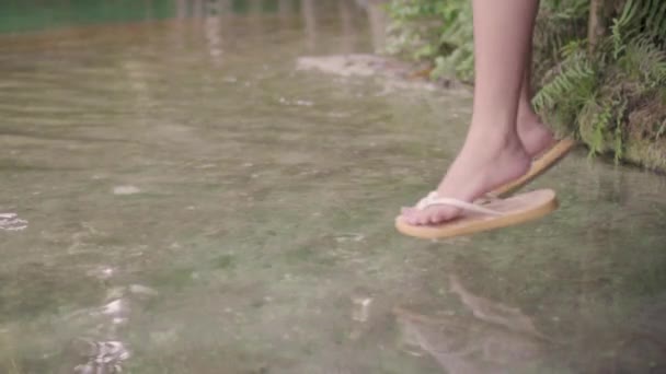 慢动作的年轻女子坐在湖边的木桥上 在水面上晃动脚 在傍晚的夏天享受生活 愉快的冒险旅行假期 — 图库视频影像