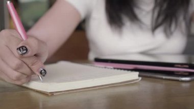 Onun fikir ve içerik üstünde defter kalem tablet, kafede smartphone ile ahşap tablo ile yazma kadın el kadar kapatın. 