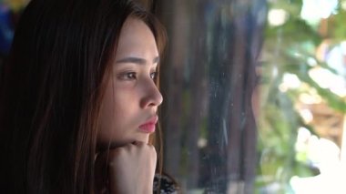 Düşünme ve evde otururken pencereden bakarak ciddi Genç Asyalı kadın kapatmak.