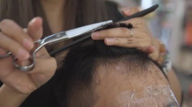 Profesyonel kuaför kesim müşteri saç makas ve tarak yavaş hareket ile. Kuaför kırpma saç makas ve yüz koruyucu maske ile client için kapatın. El atış.