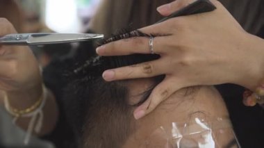 Profesyonel kuaför kesim müşteri saç makas ve tarak yavaş hareket ile. Kuaför kırpma saç makas ve yüz koruyucu maske ile client için kapatın. El atış.