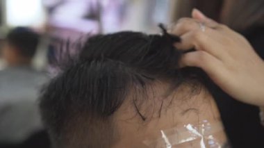 Profesyonel kuaför kesim müşteri saç makas ve tarak yavaş hareket ile. Kuaför kırpma saç makas ve yüz koruyucu maske ile client için kapatın. El atış.