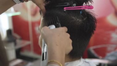 Profesyonel kuaför saç kesme makinesi ile müşteri saç kesme. Erkek saç kesimi ile tıraş. Düzeltici saç yakın çekim. Yavaş hareket ve el atış.