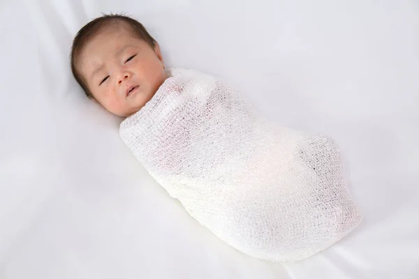 Adorable newborn baby in white wrap on white blanket background. — Stock Photo, Image