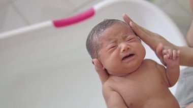 Sevimli asya yenidoğan kız organik şampuan ile saç yıkama ve evde banyoda beyaz plastik küvet babası tarafından banyo alıyor. Bebek ürünleri. Yeni doğan bebek için hijyen ve sağlık.