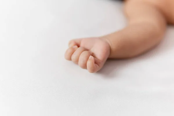 Újszülött kéz a fehér takaró, miközben alszik ágyon. — Stock Fotó