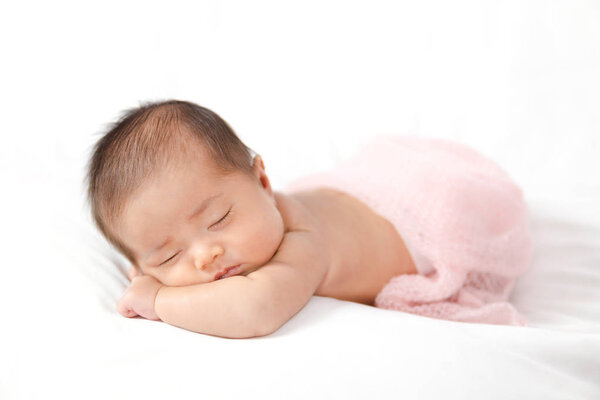 Adorable asian newborn baby in pink wrap sleeping on white blank