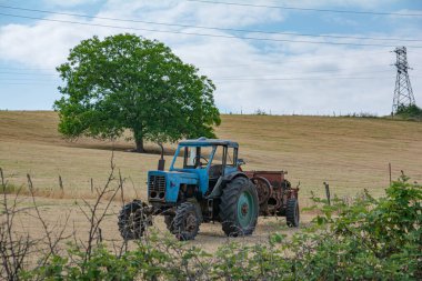 Mavi traktör alanın ortasında duruyor.