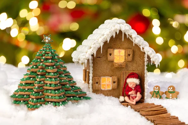 一个婴孩的复合图像在圣诞节姜饼屋前的雪景观 — 图库照片