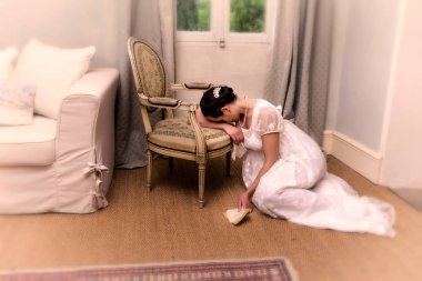 Otantik naiplik elbisesi giymiş, elinde bir mektup tutan ve antika bir sandalyeye yaslanmış genç kadını depresyona sokun.