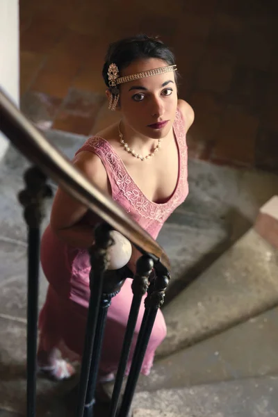 美しいです女性で本物のレトロな20代のフラッパードレスとヘッドバンドを歩いてアンティークスパイラル階段 — ストック写真