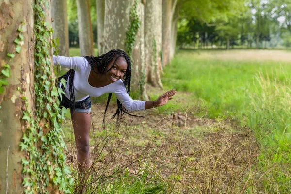 Játékos nő a fák mögött — Stock Fotó