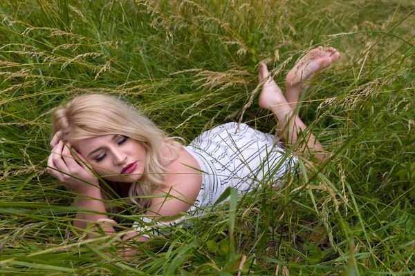 Красивая блондинка, лежащая в высокой траве — стоковое фото