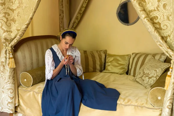 一位身穿正宗复兴服装的年轻漂亮女子躺在一座富丽堂皇的古董天篷床上 躺在一座中古时代法国城堡的金黄色卧房里 并获得了财产释放 这是荷兰大师的肖像 — 图库照片