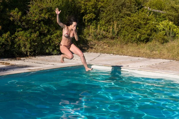 穿着蓝色比基尼的年轻漂亮的女人在一个夏季游泳池里和周围玩得很开心 — 图库照片
