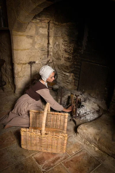 中世の農民の衣装を着た若い女性のレンブラントスタイルのルネサンスの肖像画は 解放されたフランスの城の本物の暖炉の近くで働いています — ストック写真