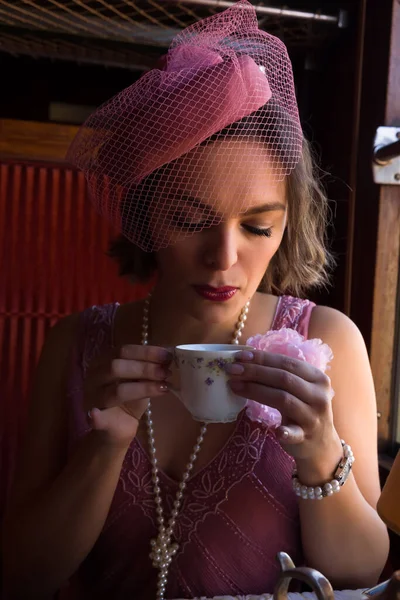1920 'lerden kalma şık elbiseli bir bayanın otantik bir 1927 model buhar treninin kompartımanında çay içişini canlandırma sahnesi.