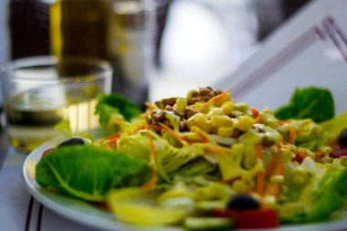 Sebzeli vejetaryen tabağı, mais, salata ve fındık, arka planda bir bardak beyaz şarap. Yiyecek ve içecek..