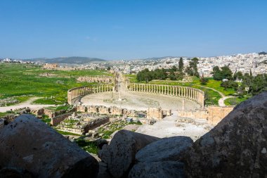 Gerasa 'nın Greko-Romen kalıntıları ve arka planda modern Jerash şehri. Oval Forum, Colonnaded Caddesi ve Cardo Maximus temiz görünüyor..